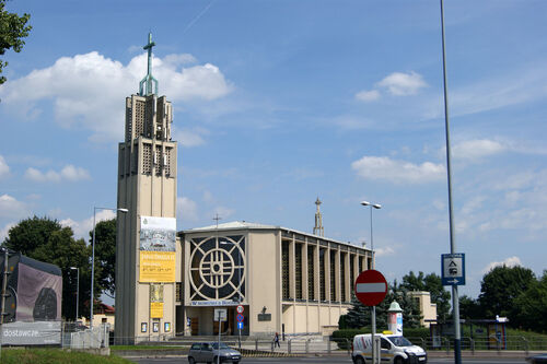 Kościół Matki Bożej Zwycięskiej w Krakowie na współczesnym zdjęciu. Kościół ma postać wysokiej hali zamkniętej z obydwu stron, wzdłuż jego długości, znacznie wyższymi wieżami zwieńczonymi Krzyżami Chrystusowymi.
