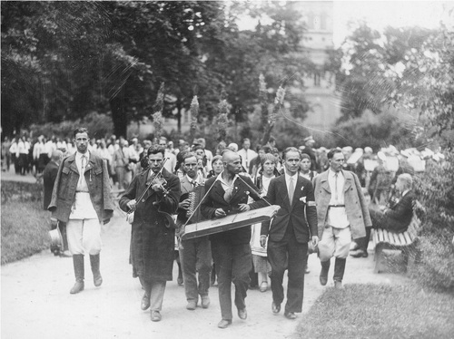 Grupa Wilnian podczas przyjęcia w ogrodzie sejmowym w trakcie II Światowego Zjazdu Polaków z Zagranicy, sierpień 1934 r. Grupa ludzi w trakcie przemarszu. Kapela z instrumentami ludowymi, osoby w strojach ludowych.