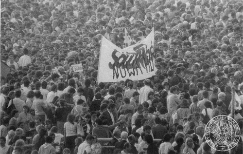 Wierni z transparentem zdelegalizowanej przez dyktaturę Wojciecha Jaruzelskiego "Solidarności" podczas uroczystości na krakowskich Błoniach 10 VI 1987 r. (sygn. IPN Kr 056/105)