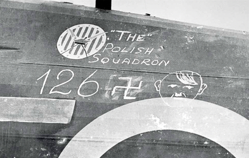 Październik 1940 r. – Odznaka Kościuszkowska na kadłubie samolotu Hawker Hurricane z Dywizjonu 303, a pod nią wypisane kredą konto zestrzeleń tej jednostki wg danych brytyjskiego dowództwa lotnictwa myśliwskiego. Kolejną ironią losu w dziejach jednostki było to, że dywizjon wsławiony skuteczną obroną Wysp Brytyjskich miał za patrona Tadeusza Kościuszkę – amerykańskiego generała, pogromcę Brytyjczyków w wojnie o niepodległość USA