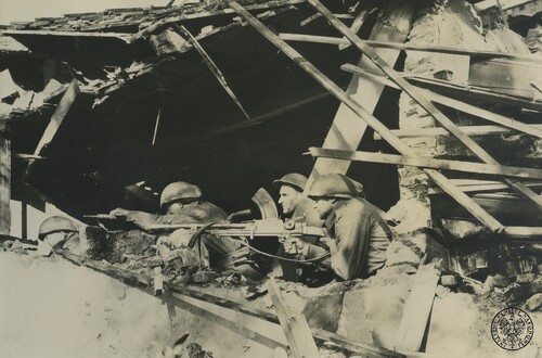 Żołnierze piechoty z polskiej 1. Dywizji Pancernej na stanowisku na dachu uszkodzonego przez artylerię budynku w Hooge Zwaluwe koło Bredy w czasie walk nad Dolnym Renem w Holandii. Na pierwszym planie żołnierz celujący z ręcznego karabinu maszynowego 7,69 mm Bren Mk I, z tyłu m.in. żołnierz strzelający z pistoletu maszynowego kal. 9 mm Sten. 1 listopada 1944 r. (?) Fot. z zasobu IPN