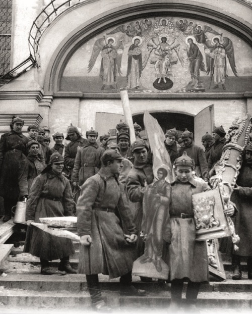 Grupa żołnierzy w bolszewickich mundurach w trakcie wynoszenia wyposażenia Cerkwii. Za ich plecami widoczna fasada świątyni.