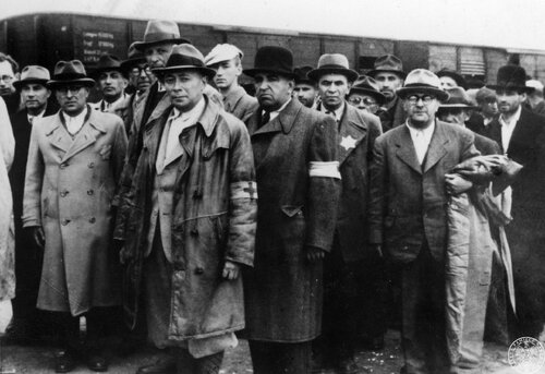 Grupa mężczyzn z transportu Żydów z Węgier, uznanych za zdolnych do pracy, stoi na bocznicy kolejowej w obozie zagłady KL Auschwitz II - Birkenau, maj 1944 r. Fot. z zasobu IPN