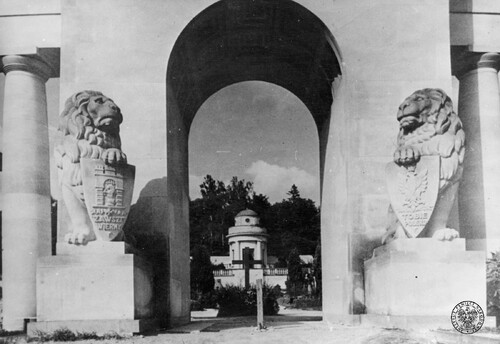Południowe wejście łuku w Pomniku Chwały na Cmentarzu Obrońców Lwowa (tzw. Cmentarzu Orląt) w okresie międzywojennym - widok od strony południowej w kierunku północnym. Po bokach kamienne lwy z tarczami zawierającymi hasła "ZAWSZE WIERNY" (po lewej) i "TOBIE POLSKO" (po prawej). Po bokach pierwsze z kolumn kolumnady. W głębi pośrodku głównej alei Mogiła Pięciu Nieznanych z Persenkówki zwieńczona krzyżem, dalej w tle Kaplica Obrońców Lwowa. Fot. z zasobu IPN