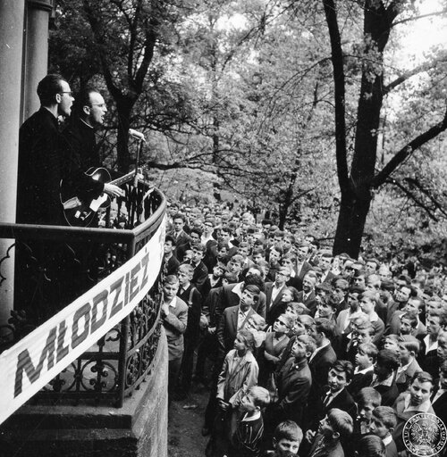 Dwaj księża stoją na balkonie kaplicy Kalwarii Piekarskiej w czasie wygłaszania nauk stanowych dla mężczyzn. Jeden z nich, ks. Stanisław Sierla, gra na gitarze i śpiewa, poniżej stoi tłum wiernych. 22 maja 1966 r. Fot. z zasobu IPN