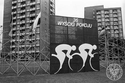 Reklama na stelażu z napisem 36 Wyścig Pokoju i sylwetkami dwóch kolarzy, ustawiona na tle wieżowców mieszkaniowych