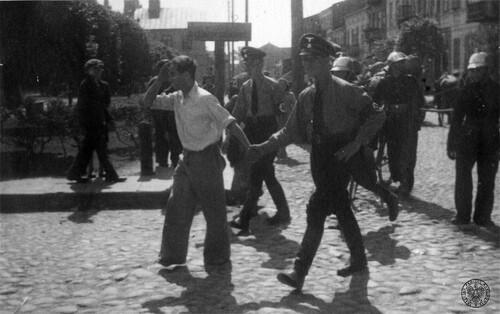 Mężczyzna aresztowany w czasie przesiedlania Żydów do getta w Kutnie w eskorcie dwóch esesmanów na Adolf-Hitler-Platz (obecnie pl. Marszałka Józefa Piłsudskiego) w Kutnie, 16 czerwca 1940 r. Fot. z zasobu IPN