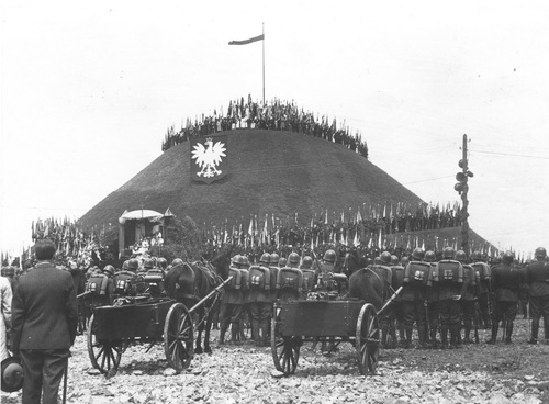 Obchody w Piekarach Śląskich 15 rocznicy powrotu Górnego Śląska do Polski. Ogólny widok Kopca Wyzwolenia podczas mszy polowej, 20 czerwca 1937 r. Ogólny widok Kopca Wyzwolenia podczas mszy polowej. Oddziały wojskowe u stóp kopca, którego zbocze zdobi tarcza herbowa z wizerunkiem Orła Białego. Niżej konstrukcja ołtarza polowego. Ludzie na szczycie kopca, zwieńczonego masztem z polską flagą.