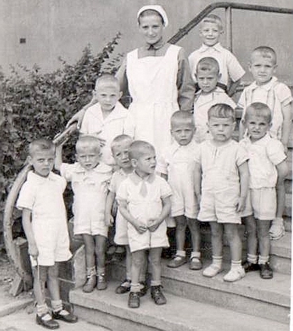 Na schodach siostra Magdalena pozuje do zdjęcia z grupką kilkuletnich chłopców.