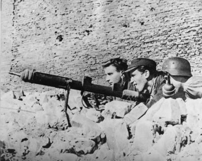 Powstańcy na stanowisku ogniowym, uzbrojeni w granatnik przeciwpancerny typu PIAT, 1944 r. Fot. AIPN