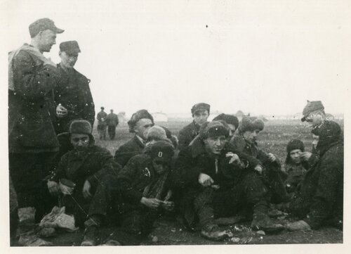 Żołnierze siedzący w grupie na ziemi.