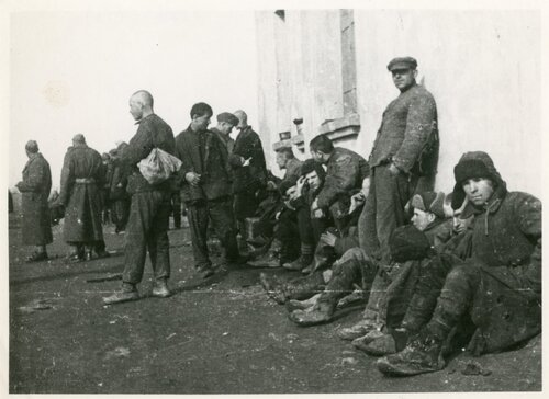 Żołnierze grupujący się pod ścianą budynku.