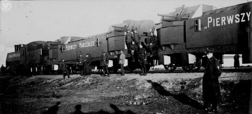 Grupa wojskowych przed wagonami pociągu.