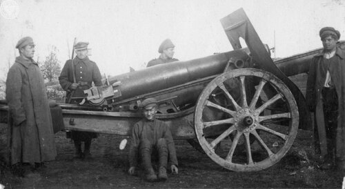Pięciu żołnierzy Wojska Polskiego przy haubicy kal. 155 mm wz. 1917, w okolicach frontu. Jeden z nich (pośrodku) siedzi oparty plecami o lawetę armatnią. Fot. AIPN