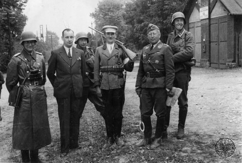 Bielsko, wrzesień 1939 r. Dwóch członków lokalnej bojówki niemieckiej (<i>Heimwehr</i>) z Bielska pozuje - do zdjęcia pamiątkowego - z 4 żołnierzami z jednostki naziemnej <i>Luftwaffe</i>. W furażerce, z mapą w ręku, stoi kapitan lotnictwa - na lewej piersi ma przypięty Krzyż Żelazny I Klasy. Fot. z zasobu IPN