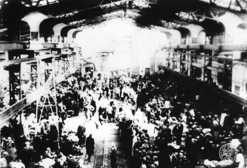 Wypełnione ludźmi wnętrze jednej z hal pofabrycznych w „Durchgangslager 121 Pruszków”. Zdjęcie nieostre.