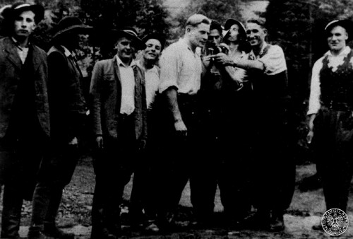 Grupa partyzantów z oddziału mjr. Józefa Kurasia "Ognia" (stoi w środku, w białej koszuli), prawdopodobnie podczas chrzcin w Waksmundzie. Fot. z zasobu IPN