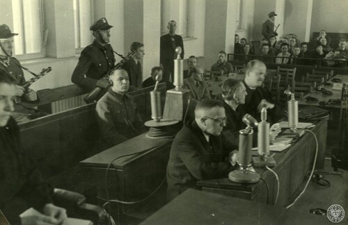 Rudolf Höss (pośrodku, w słuchawkach), były komendant KL Auschwitz-Birkenau, siedzi na ławie oskarżonych w czasie swojego procesu przed Najwyższym Trybunałem Narodowym, marzec 1947. W pierwszym rzędzie siedzą m.in. obrońcy z urzędu Tadeusz Ostarzewski i Franciszek Umbreit. Fot. z zasobu IPN