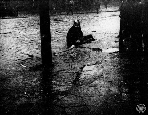 Gdańsk, 17 grudnia 1970 r. Człowiek - leżący na ulicy i podtrzymywany przez innego (niezidentyfikowanego) człowieka - jedna z ofiar masakry mieszkańców miasta dokonanej przez reżim Władysława Gomułki. Fot. z zasobu IPN