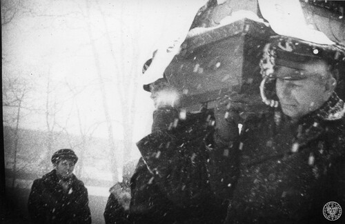 Pogrzeb Joachima Gnidy, jednego z górników zamordowanych przez reżim Jaruzelskiego podczas pacyfikacji KWK „Wujek”; 7 stycznia 1982 r. Mężczyźni niosą trumnę na cmentarz obok kościoła ewangelicko-augsburskiego pw. św. Jana w Mikołowie. Fot. z zasobu IPN
