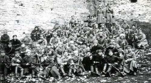 Oddział Stanisława Bułaka-Bałachowicza pod murami twierdzy Izborsk (niedaleko Pskowa; do 1940 roku w granicach niepodległej Estonii, obecnie - Rosji), październik-listopad 1919 roku. Duża grupa uzbrojonych żołnierzy, umundurowanych przeważnie w typie wzorów armii rosyjskiej, siedzi lub stoi pod murami twierdzy.