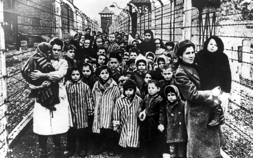 Dzieci - więźniowie obozu koncentracyjnego Auschwitz-Birkenau opuszcza teren obozu macierzystego (tzw. KL Auschwitz I) po uwolnieniu przez wojska sowieckie. Idą między dwoma ogrodzeniami z drutu kolczastego rozwieszonego na betonowych słupach. Na przodzie najmłodsze dzieci trzymające się za ręce, część ubrana w pasiaki... Fot. z zasobu IPN
