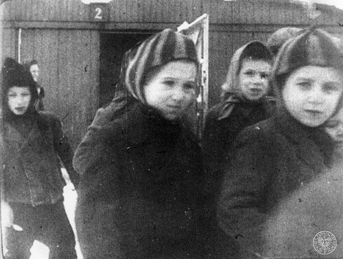 Grupa dzieci opuszcza barak nr 2 obozu koncentracyjnego Auschwitz-Birkenau po oswobodzeniu obozu przez Armię Czerwoną, 27 stycznia 1945 r. Reprodukcja kadru z sowieckiej kroniki filmowej. Fot. z zasobu IPN