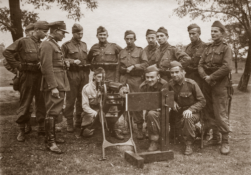 Kadeci z Korpusu Kadetów nr 3 w Rawiczu w mundurach drelichowych podczas nauki strzelania karabinem maszynowym Maxim wz. 1908 na podstawie saneczkowej. Szósty od prawej stoi kadet Łukasz Ciepliński.