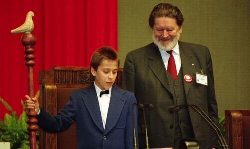 Chłopiec stoi obok Aleksandra Małachowskiego za stołem marszałkowskim, obok laski marszałkowskiej