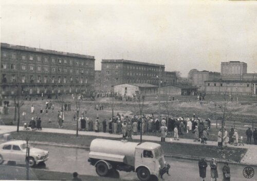 Nowa Huta, 27 kwietnia 1960 r., obrona krzyża ustawionego przy ul. Karola Marksa (obecnie Ludźmierska). Plac Teatralny; za jezdnią duża grupa osób zebrana wokół krzyża. Po prawej stronie, w tle, budynek Teatru Ludowego; po lewej widoczne bloki Osiedla Teatralnego. Fot. z zasobu IPN