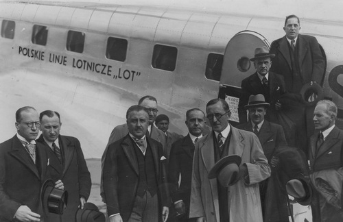 Grupa mężczyzn pozuje do zdjęcia przed samolotem z napisem: Polskie Linie Lotnicze LOT