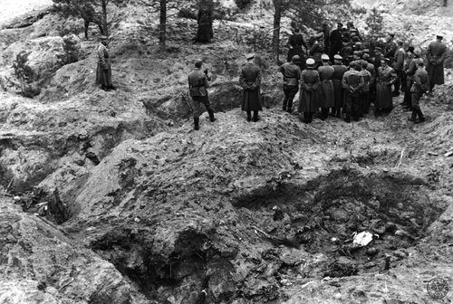 Ekshumacje zamordowanych przez NKWD oficerów Wojska Polskiego w Katyniu, kwiecień 1943. Komisja ekshumacyjna w otoczeniu oficerów Wehrmachtu stoi nad dołami śmierci (prawy górny róg). Wszędzie rozkopane doły śmierci z ciałami polskich oficerów zamordowanych w kwietniu 1940 roku przez NKWD. Fot. z zasobu IPN