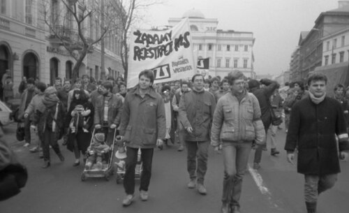 Grupa ludzi (z transparentami) idących ulicą