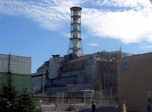 Widok obiektów strefy przemysłowej. W centrum budynek z wysokim elementem typu komin lub wieża