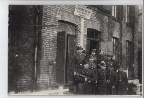 Grupa żołnierzy pozująca do zdjęcia przed wejściem do ceglanego budynku