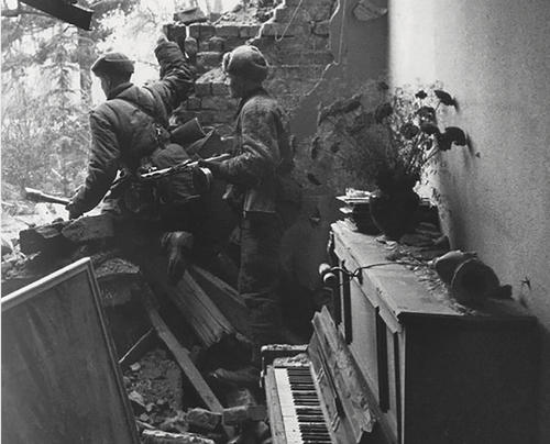 Dwóch uzbrojonych mężczyzn w mundurach w ruinach zburzonego budynku