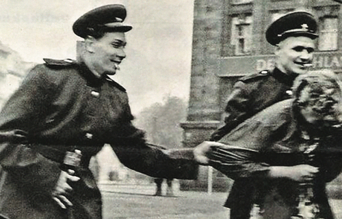 Dwóch mężczyzn w mundurach chwyta za kurtkę kobietę