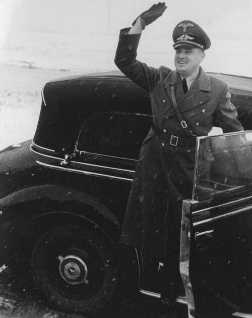 Mężczyzna wysiadający z samochodu z uniesioną prawą ręką w geście nazistowskiego, hitlerowskiego pozdrowienia