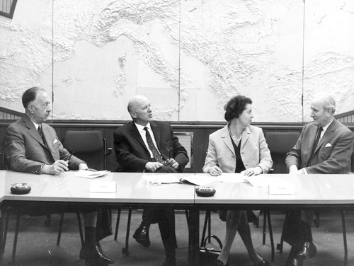 Trzech mężczyzn i kobieta prowadzący wzajemną rozmowę za stołem typu prezydialnego. W tle ściana ze zdobieniem odwzorowującym kształt kontynentu europejskiego.