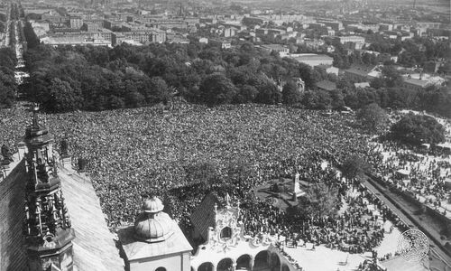 Zdjęcie przedstawiające &quot;widok z lotu ptaka&quot;, na którym tłumy ludzi gromadzą się przed murami klasztoru.