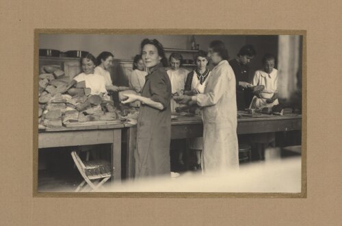 Grupa kobiet w fartuchach stojących przy ladzie zapełnionej bochenkami chleba