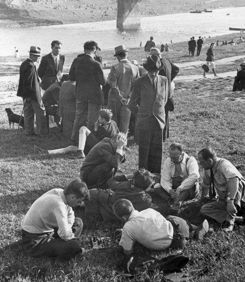 Mieszkańcy podczas odpoczynku nad Wisłą. Na pierwszym planie dwaj mężczyźni grający w szachy.