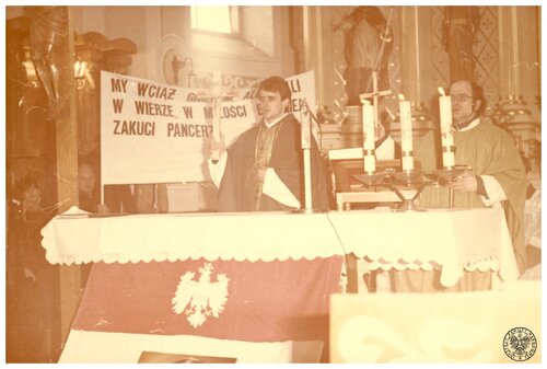 Księża stojący za ołtarzem i trzymający w prawych dłoniach krzyże