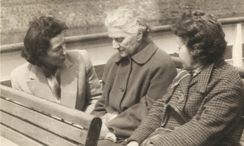 Trzy kobiety siedzące na ławce i rozmawiają ze sobą