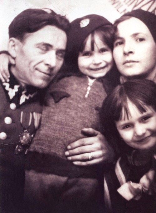 Zdjęcie rodzinne; tata w mundurze wojskowym; uśmiechnięta, dokazująca dwójka dzieci; mama z nieco poważną miną