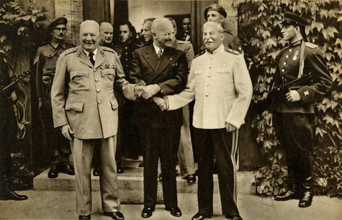 Premier Wielkiej Brytanii Winston Churchill, prezydent USA Harry Truman i sowiecki dyktator Józef Stalin ściskaja sobie dłonie, pozując przed fotoreporterami.