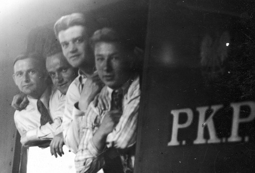 Czterech mężczyzn wyglądających przez okno pociągu.
