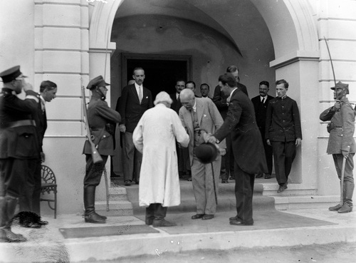 Na schodach rezydencji prezydent ściska dłoń starszego mężczyzny w chłopskiej sukmanie. Obok dygnitarze i wojskowi.