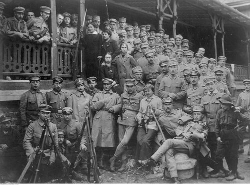 Grupa umundurowanych mężczyzn pozuje do zdjęcia na schodach. Część stoi pod schodami, część nad. Pomiędzy nimi, w środkowych rzędach z lewej strony zdjęcia, stoją cztery kobiety