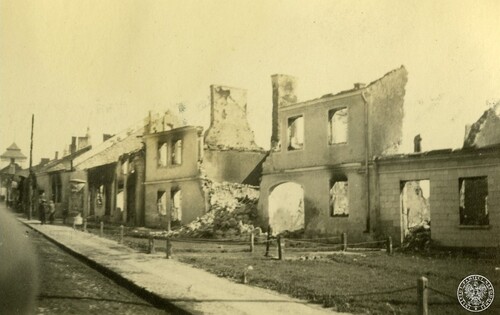 Zniszczone i wypalone w trakcie walk budynki wzdłuż jednej z ulic w Pińczowie - widok z przejeżdżającego samochodu niemieckiego. Po lewej w głębi na chodniku 2 idących ludzi w cywilnych ubraniach (odwróceni tyłem), w tle - wieża